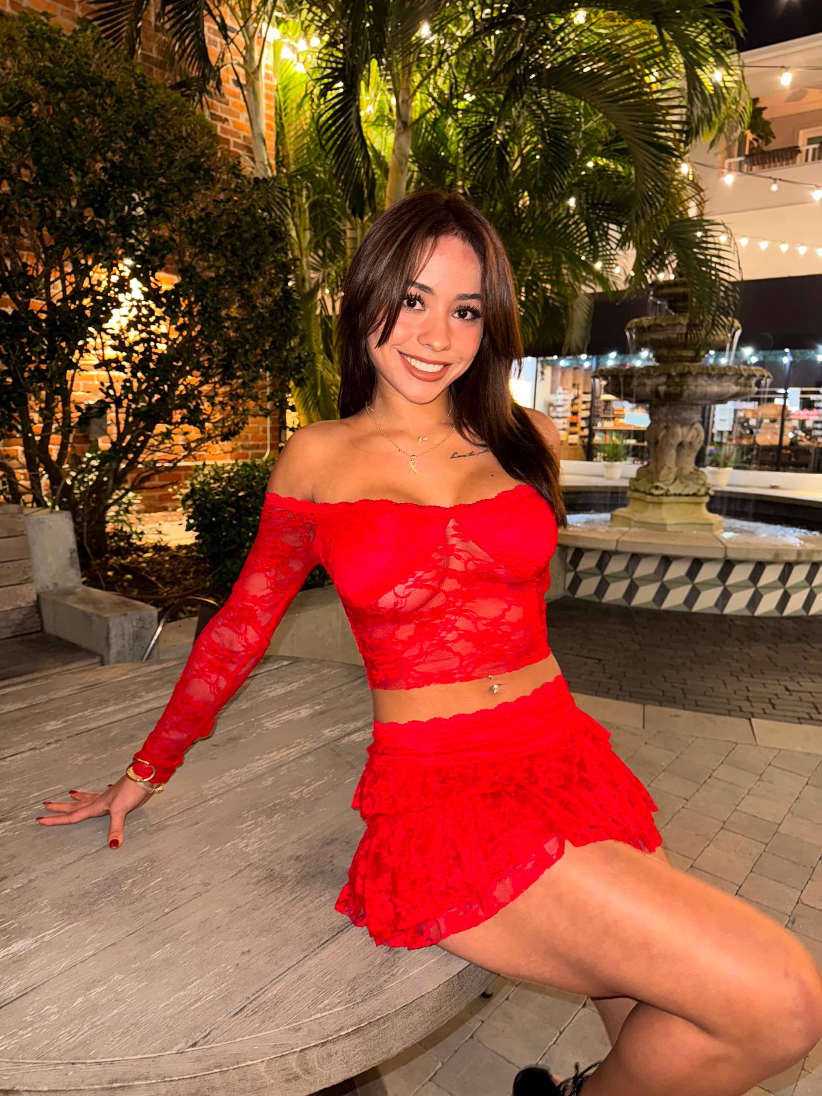 Ximena Saenz in a red lace outfit at a Miami courtyard